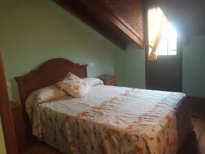 A bedroom with a wooden bed frame, a floral bedspread, and a nightstand.