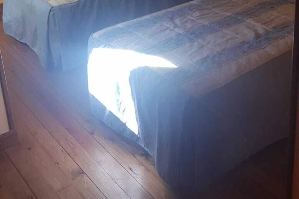 Una habitación con dos camas individuales, un radiador y suelo de madera.