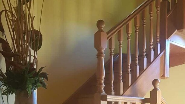 Eine Holztreppe mit Handlauf und Spindeln, die zu einer oberen Etage führt.