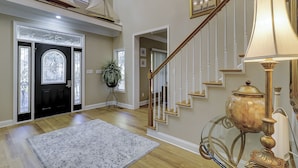 A spacious foyer with a grand staircase, a decorative lamp, and a potted plant. - 109 South Forest Beach - Steps away from your toes in the sand! (Hilton Head Island)