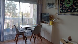 A room with a dining table, two chairs, a TV, and a decorative wall piece. - Studio 2 Pers. Pines View in Building Facing sea Baie de La Baule (La Baule-Escoublac)