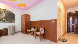 A hotel room with a kitchenette, a wooden wardrobe, a seating area with chairs, and a large wall mural. - Happy Home (Ho Chi Minh Municipality)