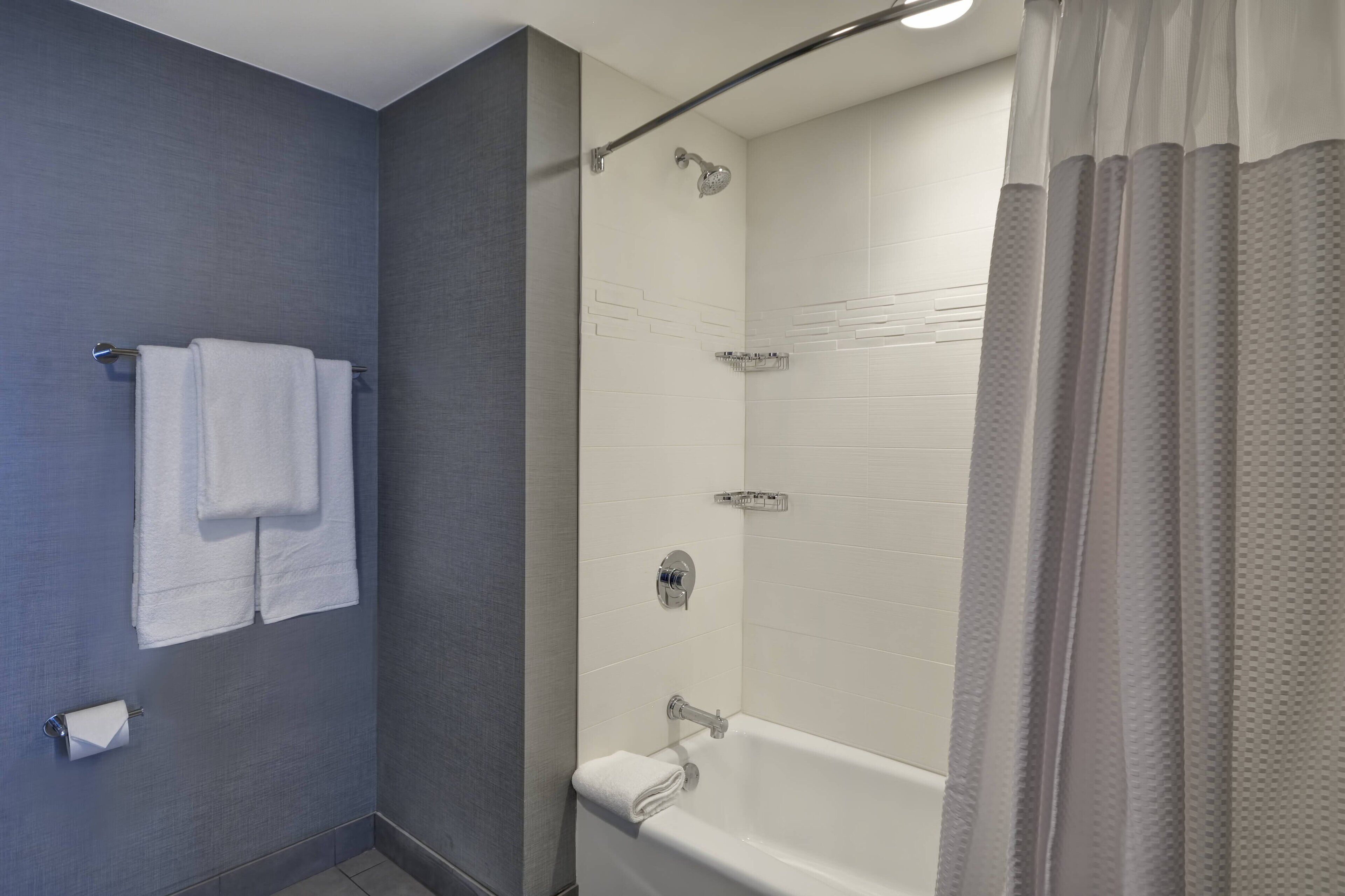 Un baño moderno con bañera, ducha y perchero para toallas.