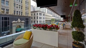 A modern hotel lobby with a large seating area, a decorative planter with red flowers, and a view of the cityscape. - Residence Inn by Marriott New Orleans French Quarter Area/Central Business District (New Orleans)