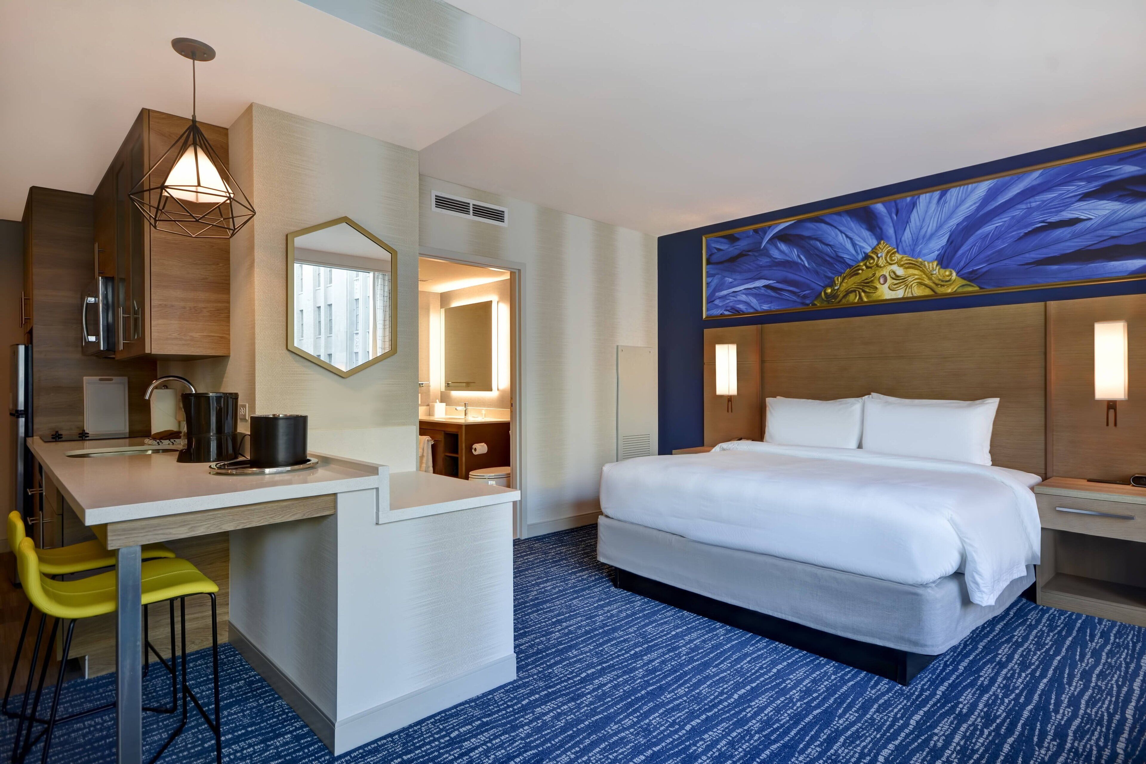 Ein Hotelzimmer mit einem Bett, einem Schreibtisch mit Stuhl, einem Waschbecken und einem Spiegel.