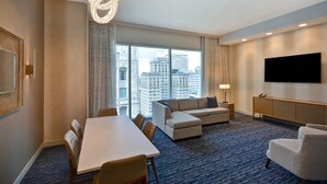 A hotel room with a large window, a dining table, a sofa, a TV, and a minibar. - Residence Inn by Marriott New Orleans French Quarter Area/Central Business District (New Orleans)