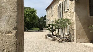Un edificio de piedra con un patio de grava, un árbol pequeño y cielo despejado.