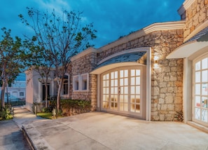 A stone house with a large arched entrance and a well-lit driveway.