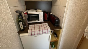 Una cocina compacta con microondas, tostadora y un refrigerador pequeño.