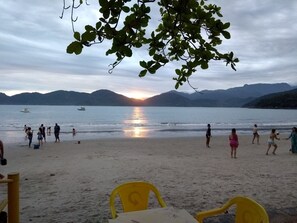 Ein Strand mit Menschen, Booten und Bergen im Hintergrund.