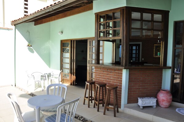 A patio area with a round table and chairs, a brick counter with stools, and a large vase.