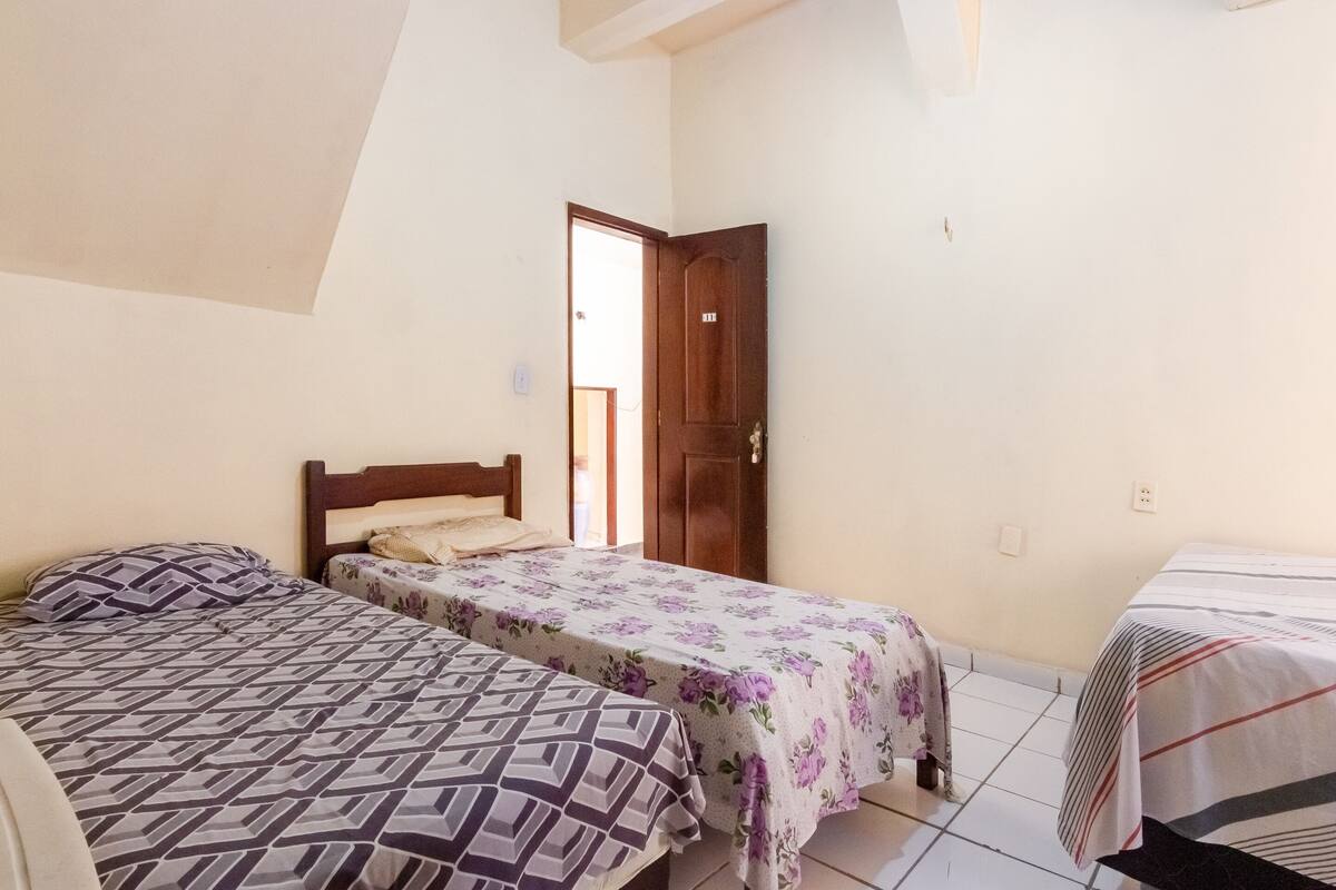 Quarto com duas camas, porta de madeira e chão de azulejos.