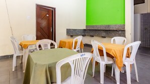 Un espace repas avec des tables et des chaises, un mur végétal et une porte en bois.