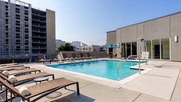 Una piscina al aire libre, sombrillas, sillones reclinables de piscina