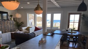 A spacious living area with a large island, a dining table, and multiple seating options. - BEACH Front w/ HOT TUB🔥 Mid Century Home! (Norfolk)