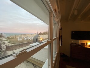 Enjoy a beach view from the large window, featuring a dune buggy and beach chairs outside.