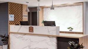 A hotel reception desk with marble countertops, wooden paneling, and pendant lighting. - Aiden by Best Western Cape Cod - West Yarmouth (West Yarmouth)