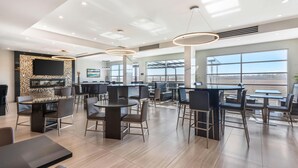 A modern dining area with high ceilings, recessed lighting, and large windows offering a view of the outdoors. - Executive Residency by Best Western Calgary City View North (Calgary)