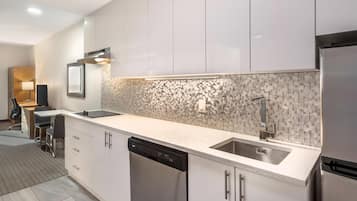 A modern kitchen with white cabinets, a dishwasher, a sink, and a tiled backsplash.