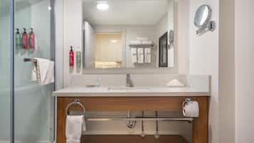 A modern bathroom with a glass shower enclosure, a wooden vanity, a large mirror, and a towel rack.