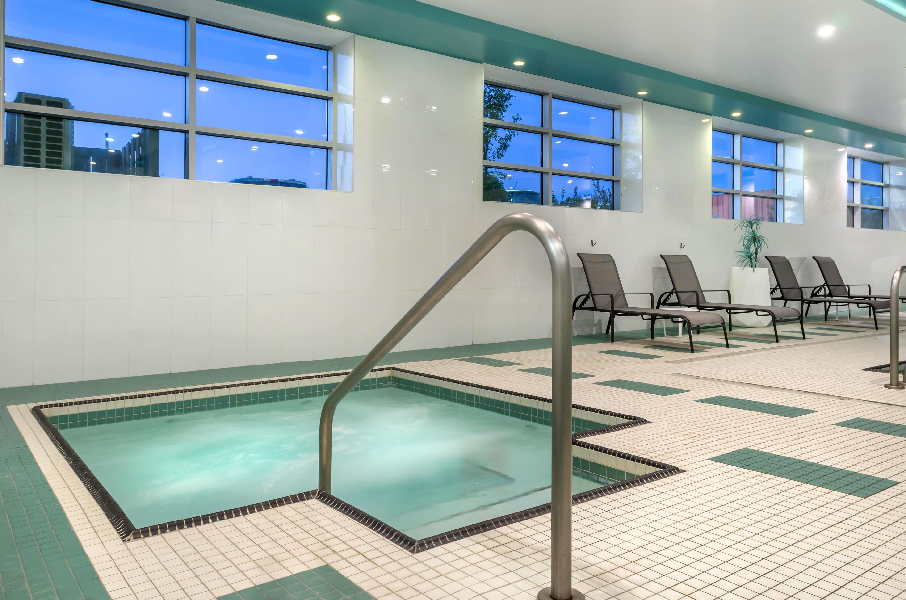 Een binnenzwembad, parasols bij het zwembad en ligstoelen