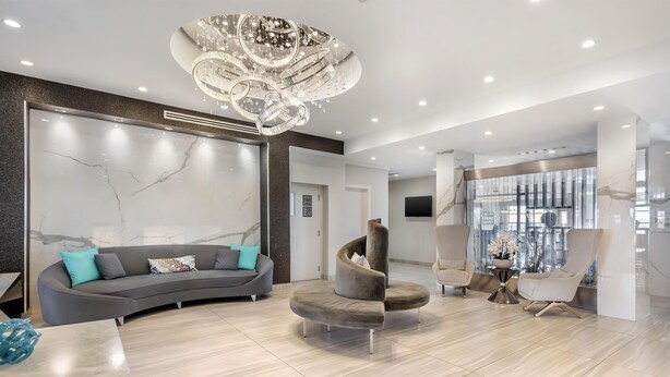 A modern living room with a curved sofa, a round chair, and a chandelier. - Executive Residency by Best Western Calgary City View North (Calgary)