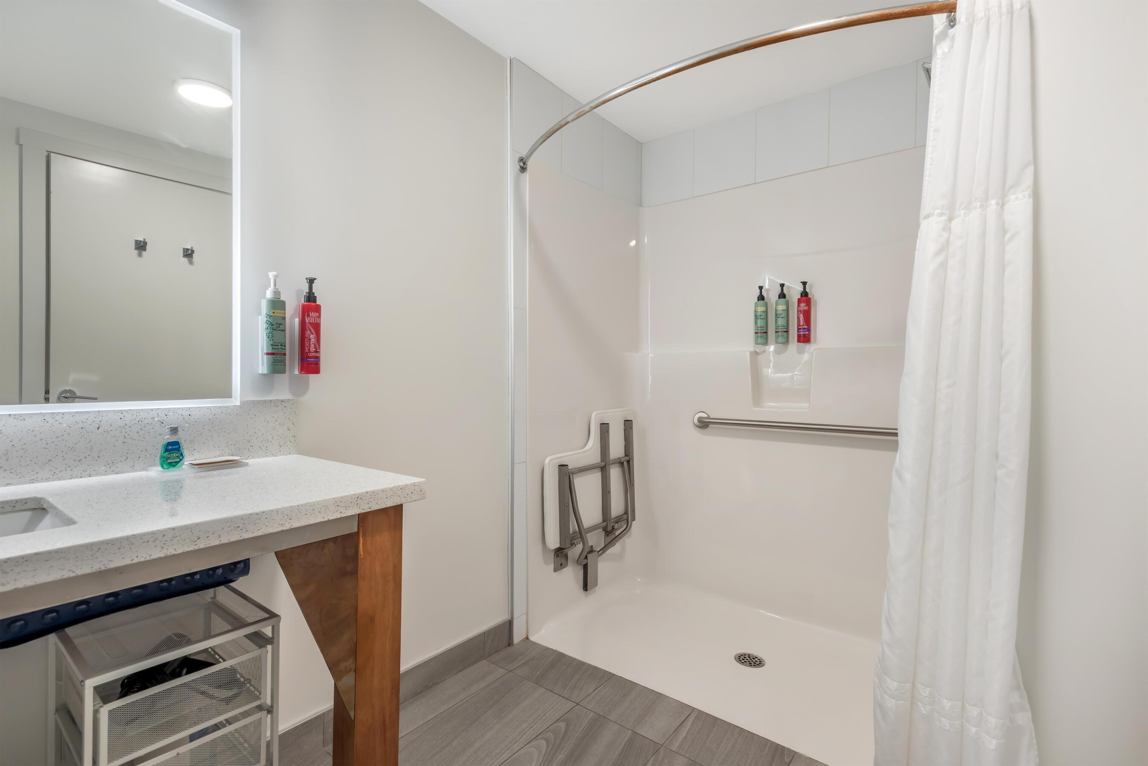 Un baño moderno con cabina de ducha de vidrio, un lavabo blanco y un espejo.