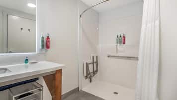 Un baño moderno con cabina de ducha de vidrio, un lavabo blanco y un espejo.
