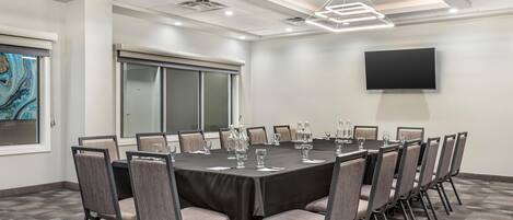 A conference room with a large table, chairs, and a flat-screen TV on the wall.