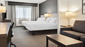 Una habitación de hotel con una cama grande, dos mesitas de noche con lámparas, un sofá, un escritorio y una silla.
