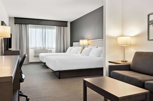 Una habitación de hotel con una cama grande, dos mesitas de noche con lámparas, un sofá, un escritorio y una silla.