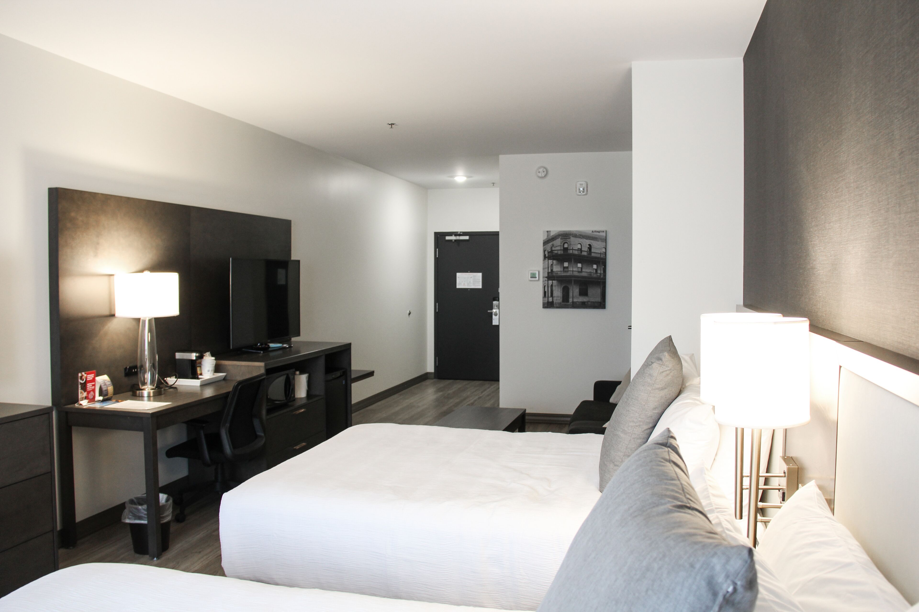 A hotel room with a bed, desk, chair, and a TV.