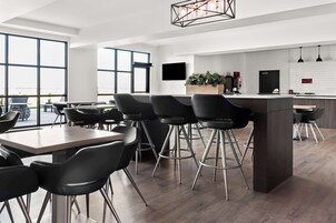 Una cocina moderna con una isla central, taburetes de bar y un amplio ventanal que proporciona luz natural.
