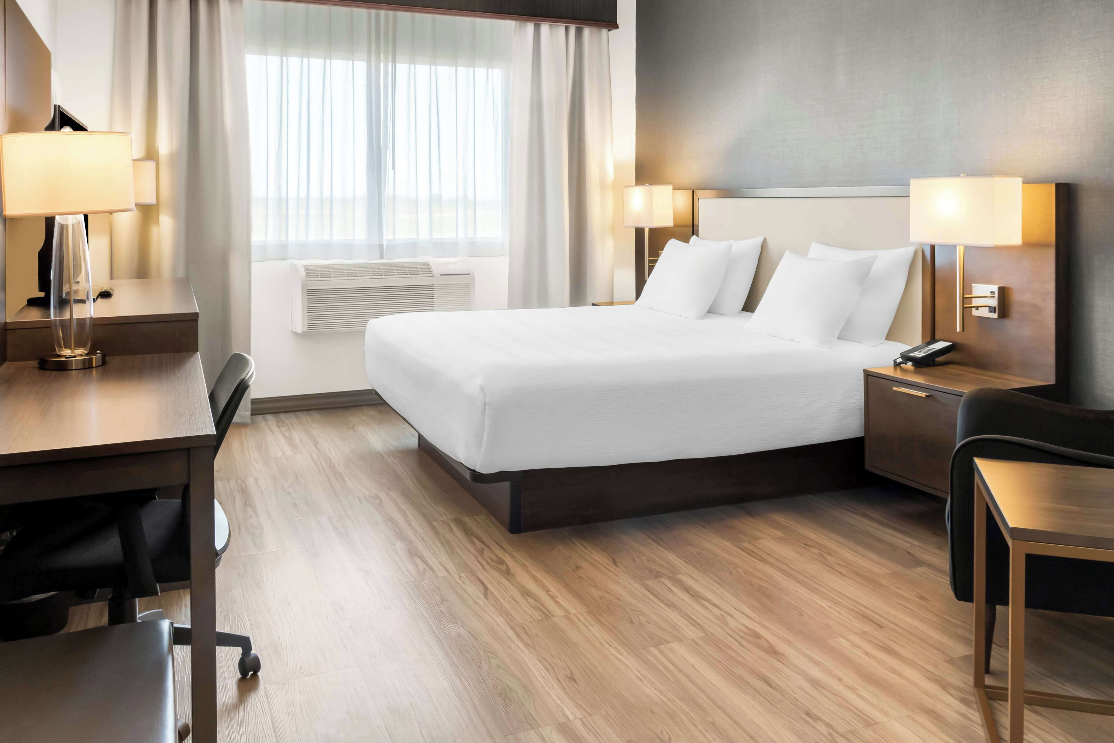 A hotel room with a large bed, bedside tables, a desk, and a chair.