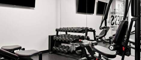 Un gimnasio con banco, mancuernas y máquina de poleas.