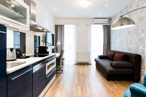 A modern kitchen with a built-in oven, a dining area with a table and chairs, and a living area with a sofa and a lamp. - Best Western Plus Celebrity Suites (Vienna)