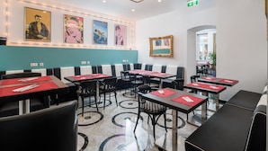 A restaurant with booths and tables, each with red placemats and cutlery. There are framed pictures on the wall and a ceiling light fixture. - Best Western Plus Celebrity Suites (Vienna)