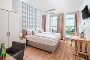 Una habitación de hotel moderna con cama, mesita de noche, lámpara y una botella de agua.