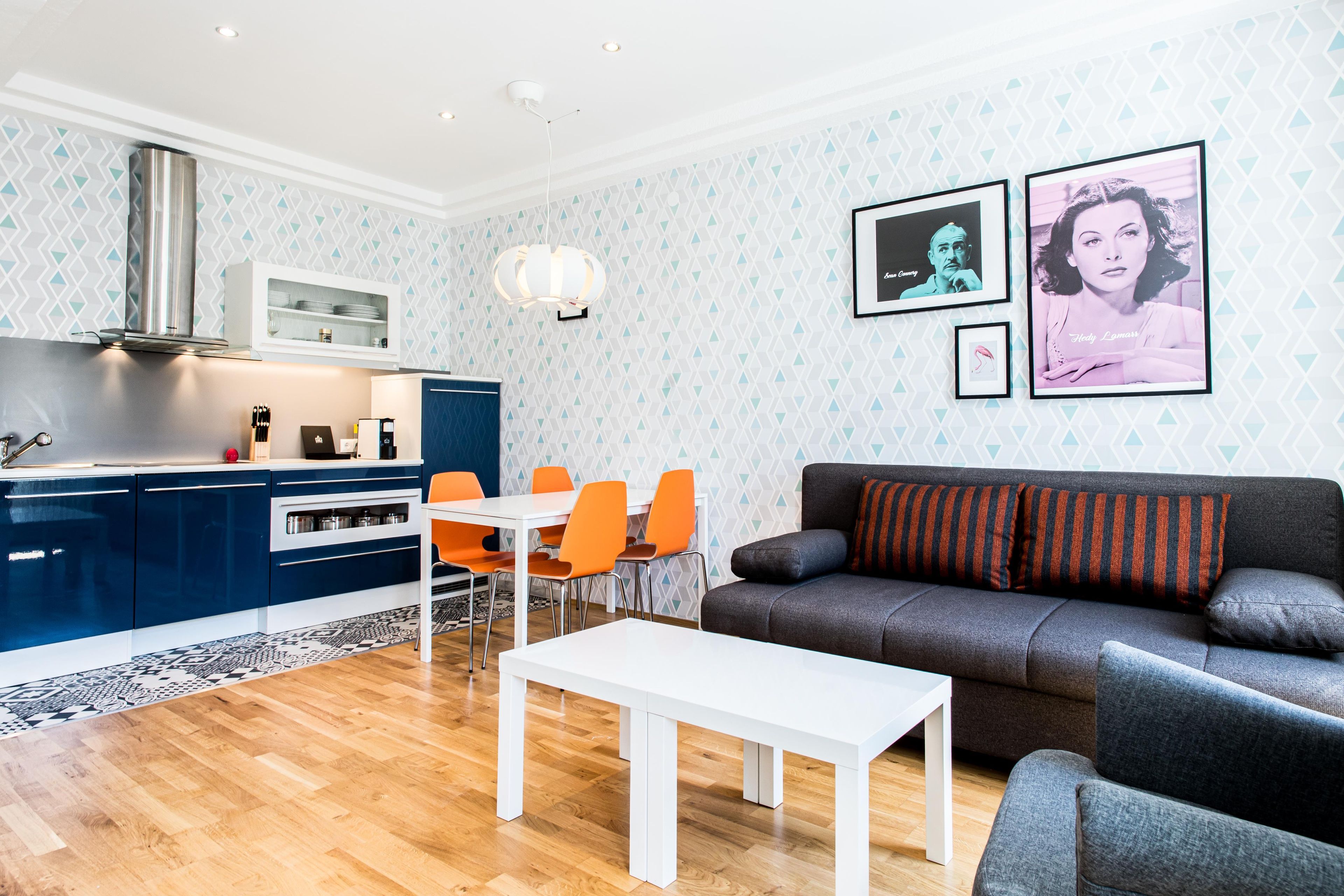 Ein stilvolles Wohnzimmer mit einem grauen Sofa, einem weißen Couchtisch und orangenen Sesseln.