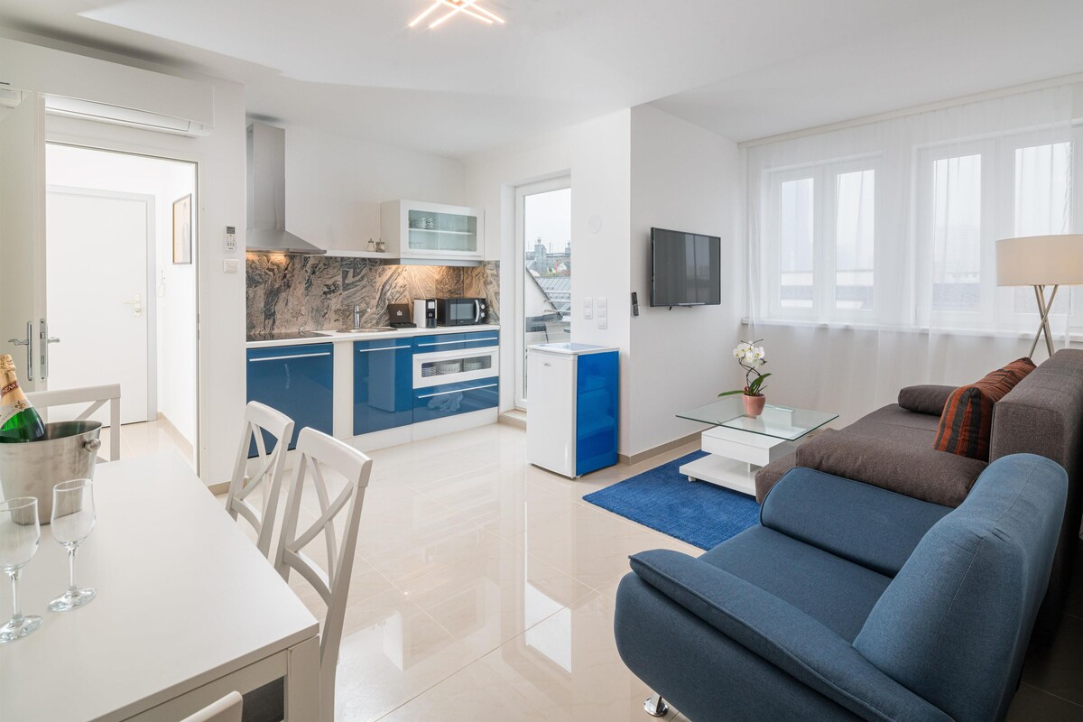 A modern apartment with a living room, dining area, kitchen, and a balcony.
