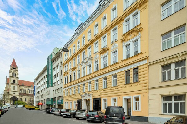 A row of yellow buildings with white windows and a church in the background. - Best Western Plus Celebrity Suites (Vienna)