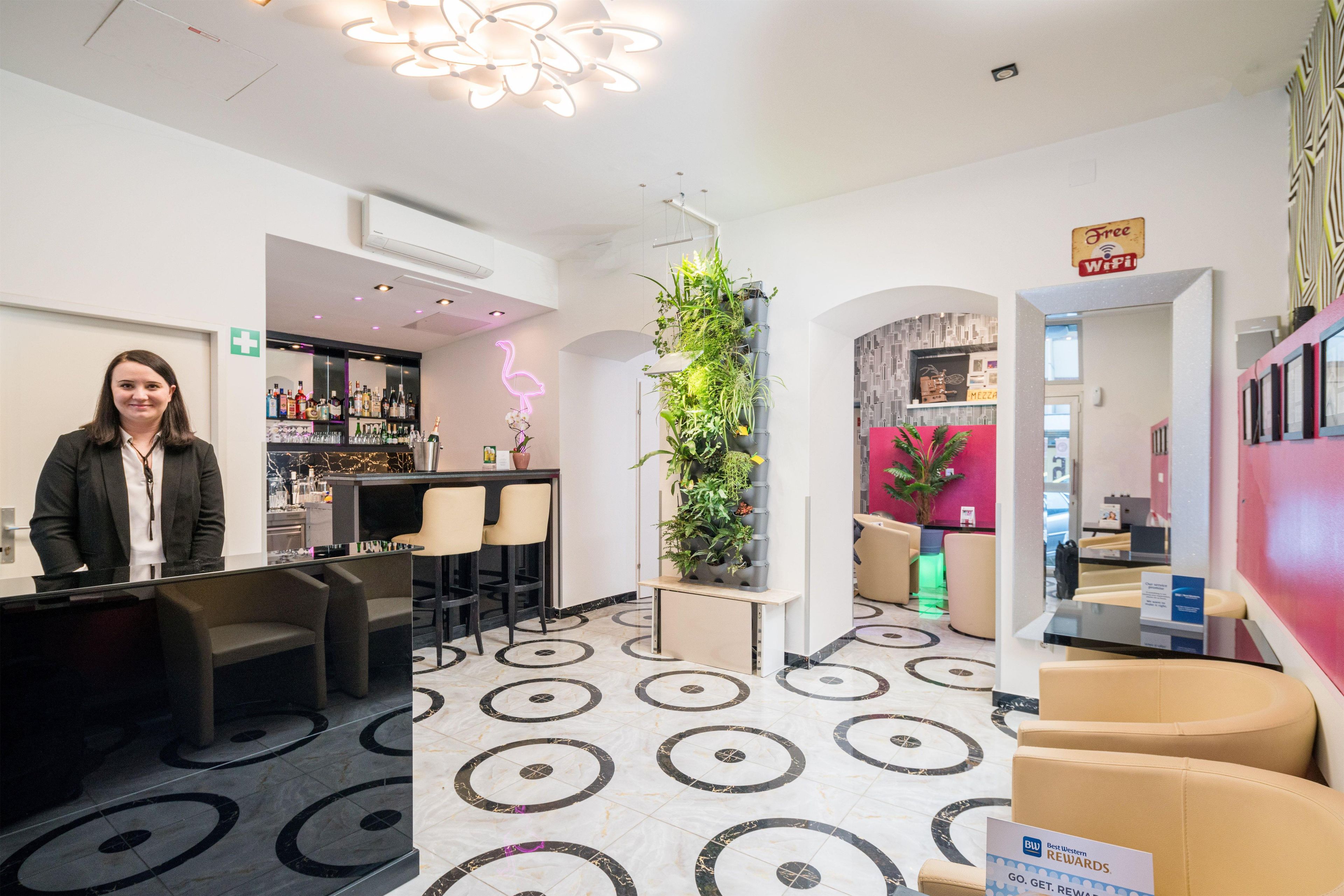 Ein Hotel-Empfangsbereich mit Bar, Sitzgelegenheiten und einer Pflanzenausstellung.