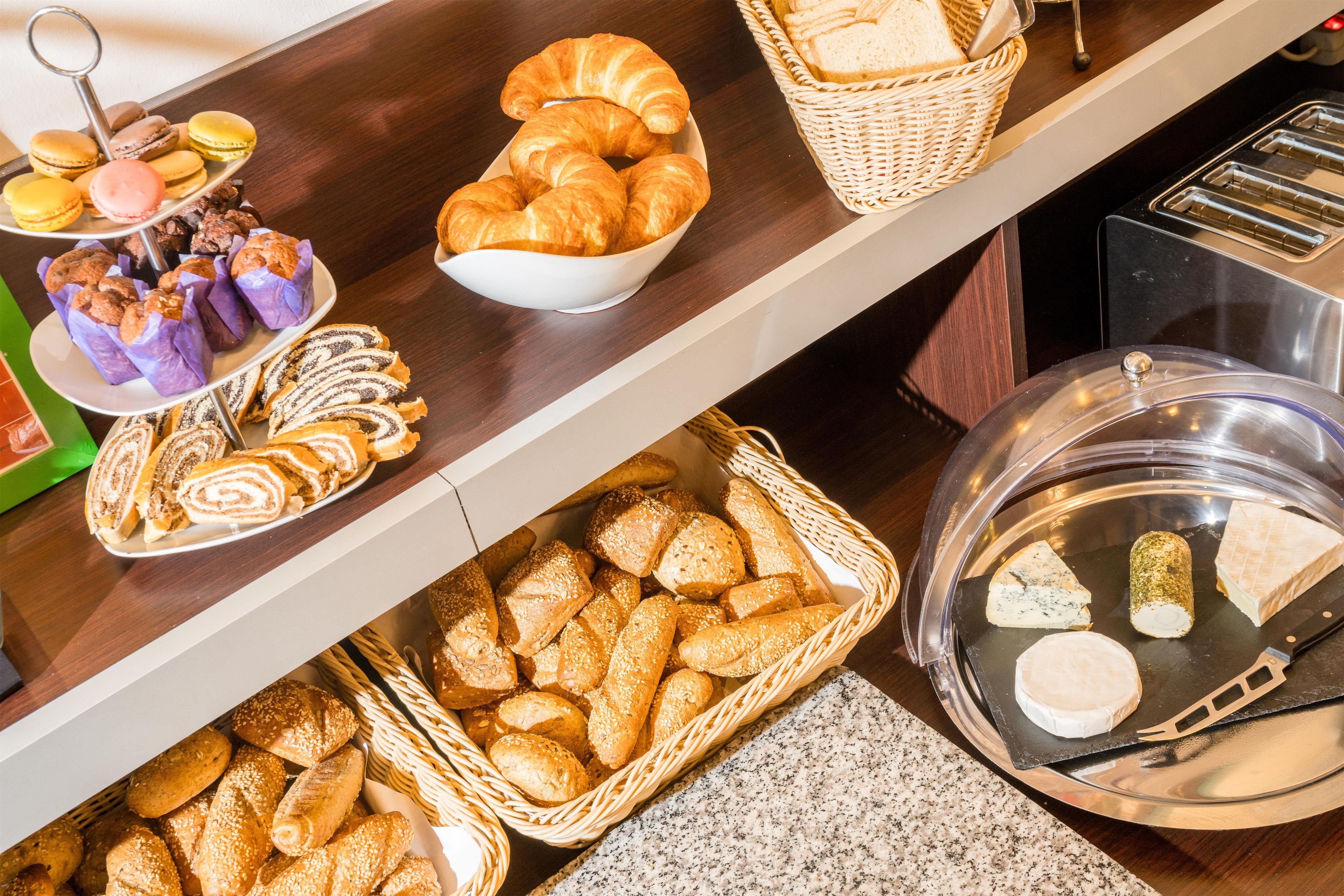 A buffet with various baked goods, including bread, pastries, and a cheese selection.