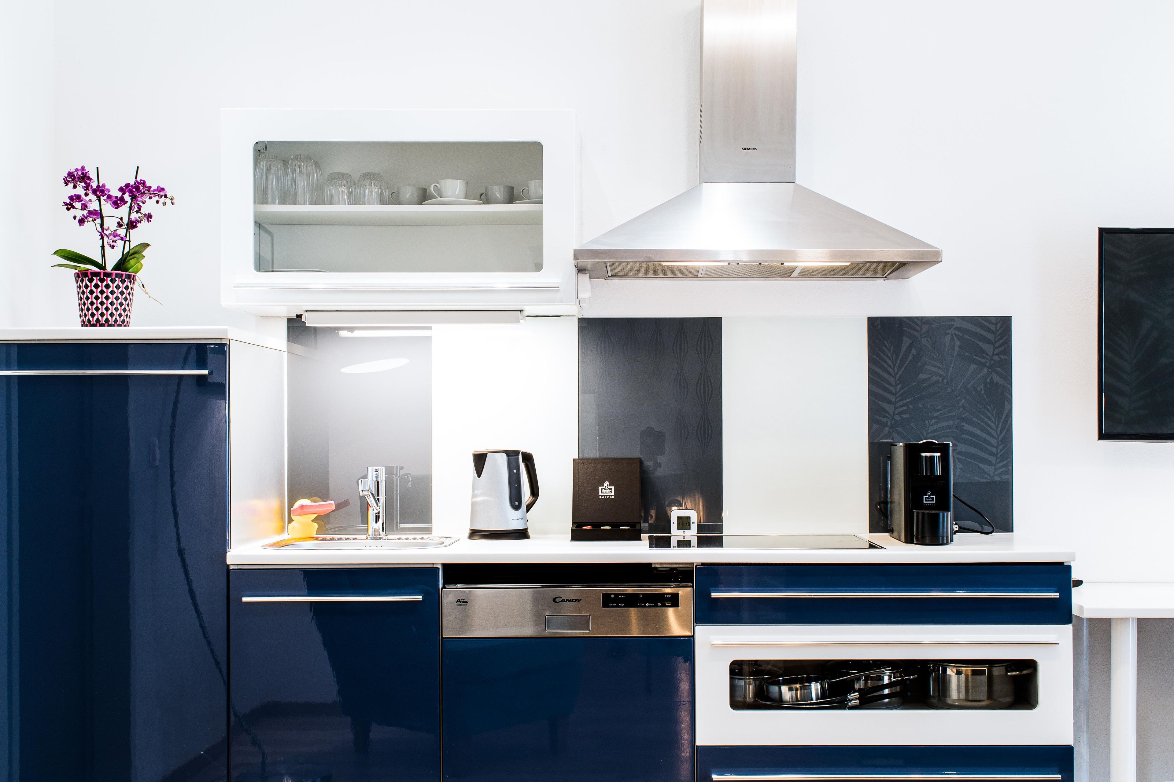 Una cocina moderna con horno empotrado, cafetera y hervidor.