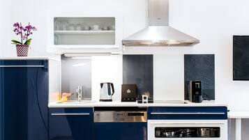 Una cocina moderna con horno empotrado, cafetera y hervidor.