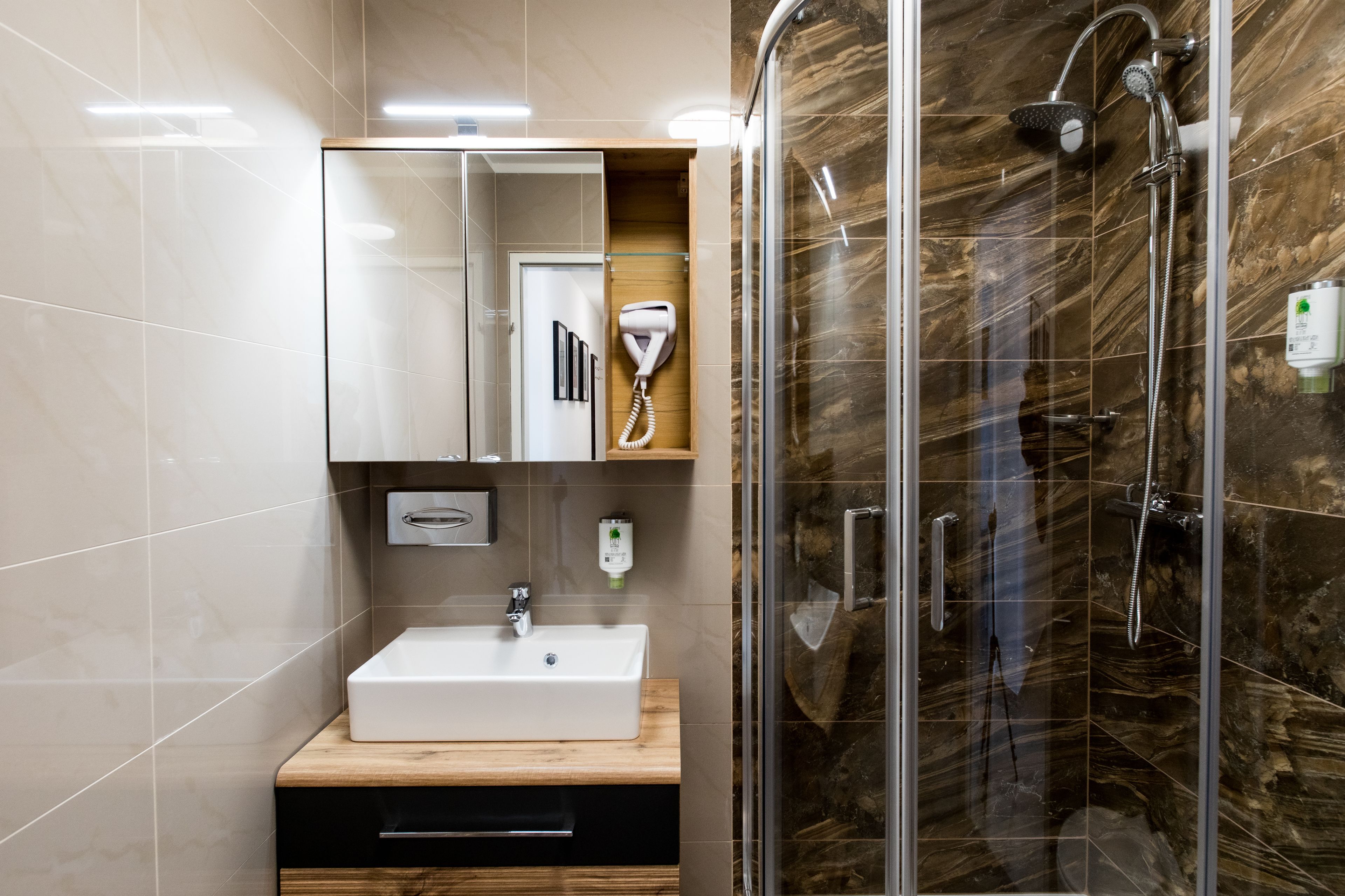 A modern bathroom with a glass-enclosed shower, a white sink, and a wooden vanity.
