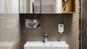 A modern bathroom with a white sink, wooden vanity, a glass shower enclosure, and a hairdryer in a wooden box. - Best Western Plus Celebrity Suites (Vienna)