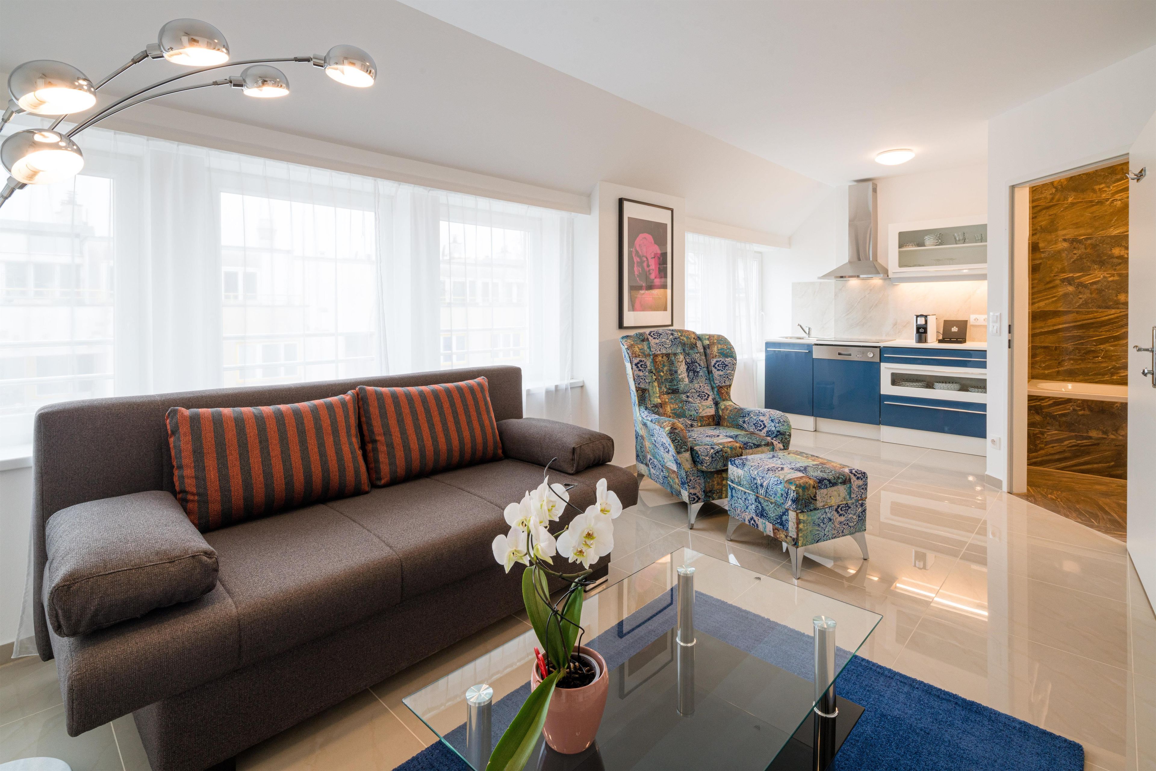 A modern living room with a sofa, armchair, and a glass coffee table.
