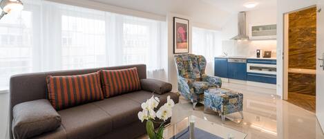 A modern living room with a sofa, armchair, and a glass coffee table.