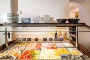 A buffet with various food options, plates, and baskets on a counter. - Best Western Plus Celebrity Suites (Vienna)